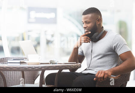 African guy thinking about what to choose on laptop screen Stock Photo