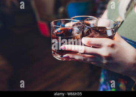 Male hands cheer with glasses of shot or liqueur. Friends drink shot or liqueur and cheers. Male hands cheer with alcohol on blurred bar background Stock Photo