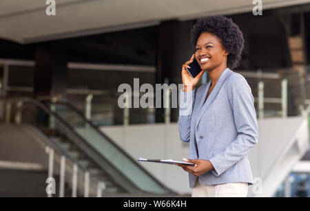African American businesswoman talking on cell phone near office building