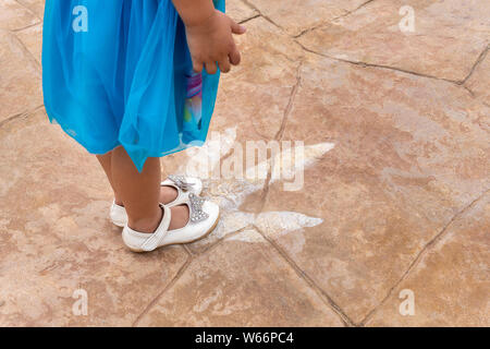 Sirindhorn Museum, Karasin Province Thailand - July 20, 2019: Girl standing on foot, dinosaur footprints Stock Photo