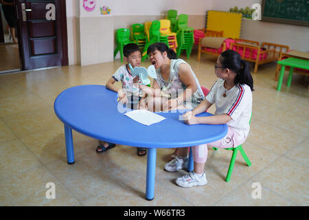 (190731) -- NANCHANG, July 31, 2019 (Xinhua) -- Liu Xiaoqing (C) tutors two deaf-mute students during a voice and speech training at the Luxi County Special Education School in Luxi County of Pingxiang, east China's Jiangxi Province, July 3, 2019. When the Luxi County Special Education School was established in 1997, Liu Xiaoqing, then a normal university graduate, applied for a post there without hesitation.   Working as a special education teacher has been challenging, as Liu's students need far more attention than their peers without physical or mental disabilities. But Liu stayed on her po Stock Photo