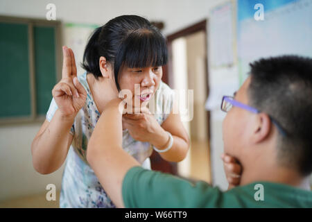 (190731) -- NANCHANG, July 31, 2019 (Xinhua) -- Liu Xiaoqing (L) places a student's hand on her throat during a voice and speech training at the Luxi County Special Education School in Luxi County of Pingxiang, east China's Jiangxi Province, July 3, 2019. When the Luxi County Special Education School was established in 1997, Liu Xiaoqing, then a normal university graduate, applied for a post there without hesitation.   Working as a special education teacher has been challenging, as Liu's students need far more attention than their peers without physical or mental disabilities. But Liu stayed o Stock Photo