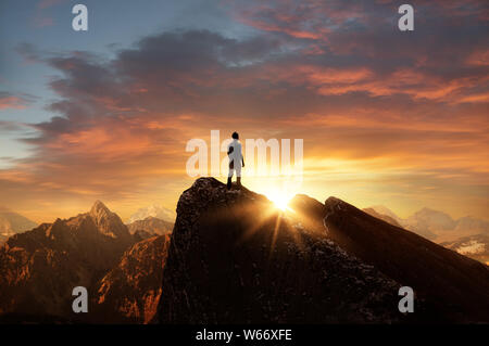 A man standing on top of a mountain as the sun sets. Goals and achievements concept photo composite. Stock Photo