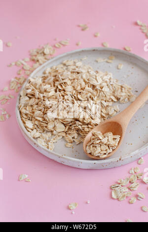 Rolled oats on a plate on light pink background Stock Photo