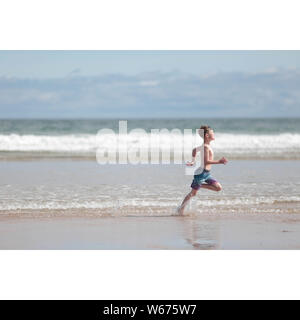 Boy running on beach in shorts Stock Photo