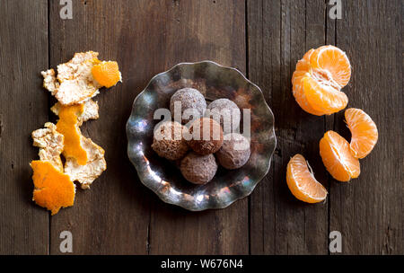 Chocolate truffles and tangerins on a wooden table Stock Photo