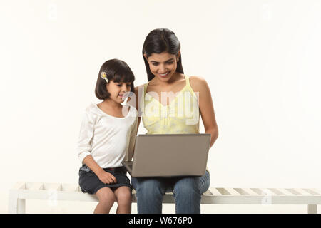 Woman using a laptop with her daughter Stock Photo