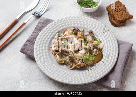 Stewed mushrooms in sauce with sour cream and cheese on a plate. Stock Photo