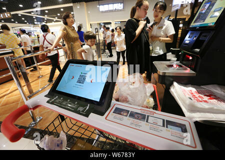 Customers use a tablet PC mounted on the handle-bar of a smart shopping cart to do the self check-out at a supermarket in Xiangyang city, central Chin Stock Photo