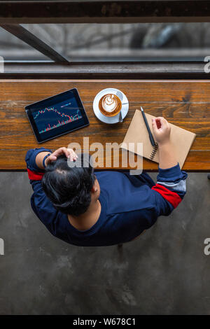 Business analyst grabbing her head while watching stock trading graph Stock Photo