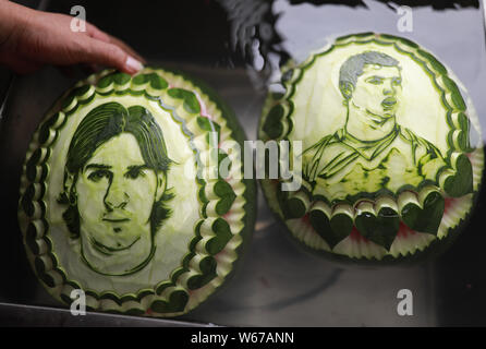 Chinese teacher Jiang Zhongmin shows watermelon carvings of (from left) Argentine football player Lionel Messi and Portuguese football player Cristian Stock Photo