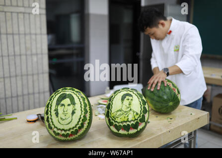 Chinese teacher Jiang Zhongmin shows watermelon carvings of (from left) Argentine football player Lionel Messi and Portuguese football player Cristian Stock Photo