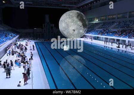 Visitors view a huge moon model during an exhibition on moon held at the National Aquatic Center or 'Water Cube' in Beijing, China, 8 July 2018.    A Stock Photo