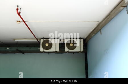 Group of condensing units of air conditioners, fire sprinkler and heat detector installed on ceiling of a building Stock Photo