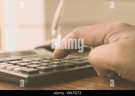 Close up of Press the right button. Calculator with finger. Fingers pressing the buttons of calculator. A businessman typing hand calculating numbers. Stock Photo