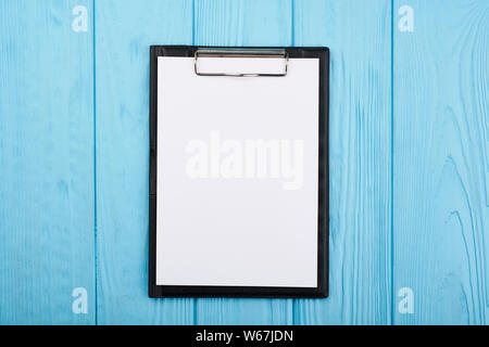 Planner on the blue wooden working table. Blank white paper on working desk Stock Photo