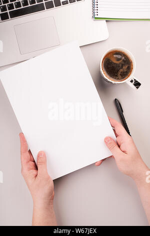 Man's hands holding blank paper on the working desk with computer and coffee Stock Photo