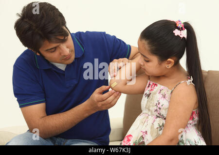 Man putting bandage on daughter,s elbow Stock Photo