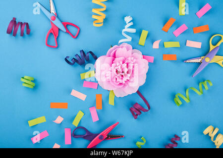 Pink flower with color papers and scissors on the blue background Stock Photo