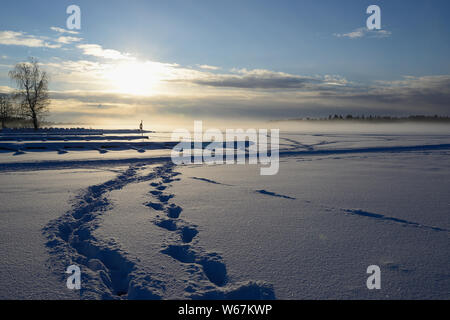 fog over winter lake in finland, sunset Stock Photo
