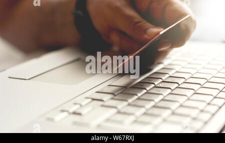 male hand holding a credit card during an internet payment transaction. Concept of e-commerce and online shopping. Stock Photo