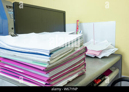 Stack of accounting documents with computer screen on desk in office Stock Photo