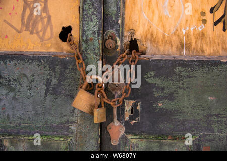 Rusty chain with padlocks on derelict, old wooden gates. Stock Photo