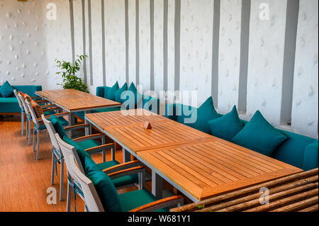 Wooden dining table with green pillows on sofa at restaurant Stock Photo