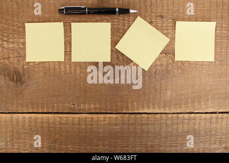 four yellow notes on a wooden table Stock Photo