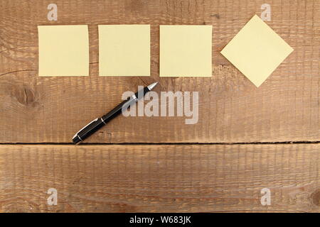 four yellow notes on a wooden table Stock Photo