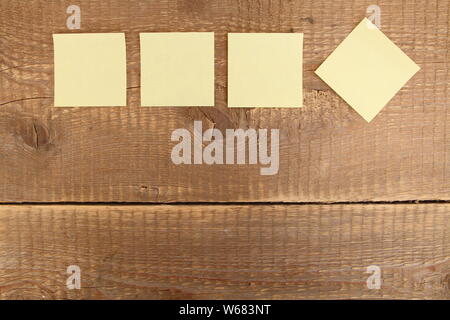 four yellow notes on a wooden table Stock Photo