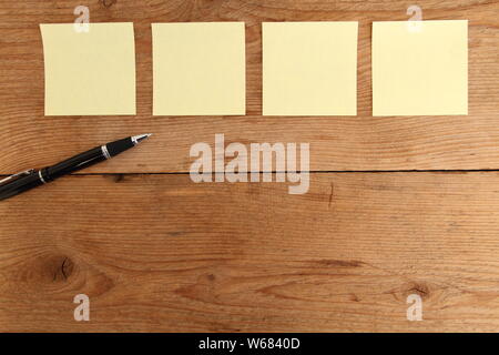 four yellow notes on a wooden table Stock Photo