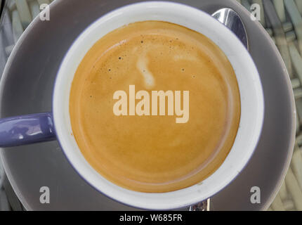 Black coffee in violet cup on cafe table Stock Photo