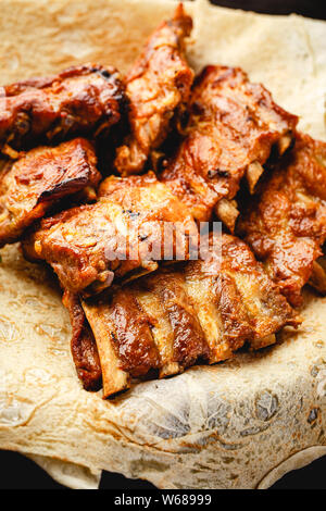 Grilled pork ribs on thin pita in plate on brown background Stock Photo