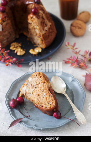 Apple pie with nuts, decorated with salted caramel and small red apples. Rustic style. Stock Photo