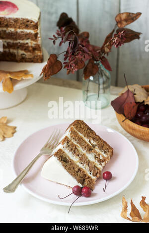 Apple cake with cream, decorated with small apples against the background of autumn composition. Rustic style. Stock Photo