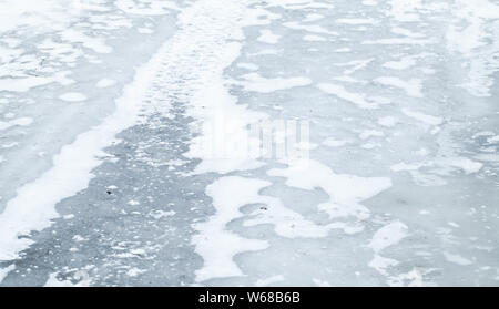 Winter transportation background with tire track on icy road covered with snow Stock Photo