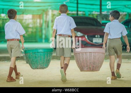 Male Students help to remove rubbish from the classroom to pile waste Stock Photo