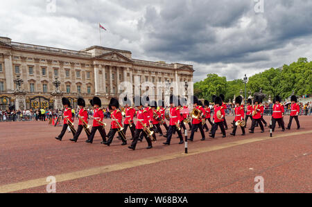 A marching band of soldiers wearing red coats and bear skin hats outside Buckingham Palace in London, England Stock Photo