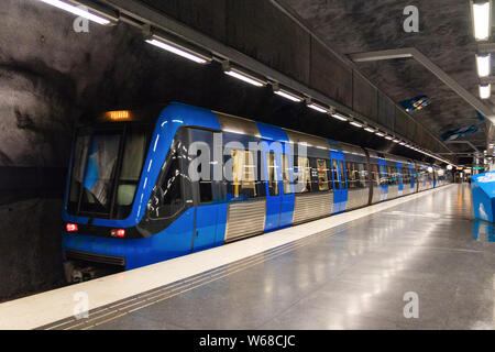 Stockholm, Sweden June 7 2019: Modern illuminated Solna Strand Underground Subway Station in gray colors with blue moving train. Stock Photo