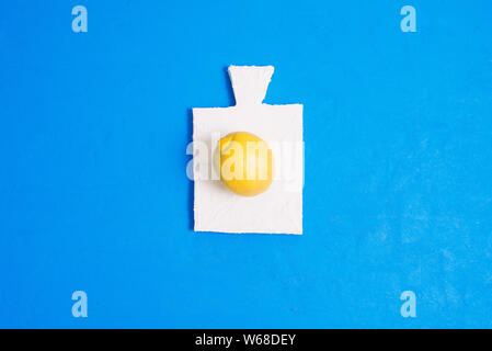 Fresh lemon lies on a small white board. Still life on blue background. Art gallery Stock Photo