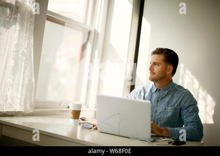 Focused young businessman working on a laptop in his office. Stock Photo