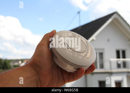 Smoke detector with a house in the background Stock Photo