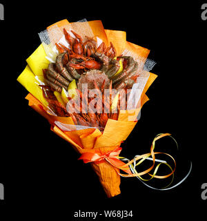 Unique bouquet consisting of large crab and boiled crawfish wrapped in orange paper on a black background Stock Photo