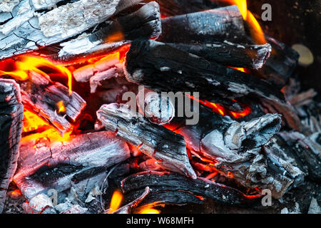 Closeup of burning and smoldering firewood. Close-up of Burning coal. Glowing embers smoldering in the fireplace. Burning log of wood close-up as abst Stock Photo