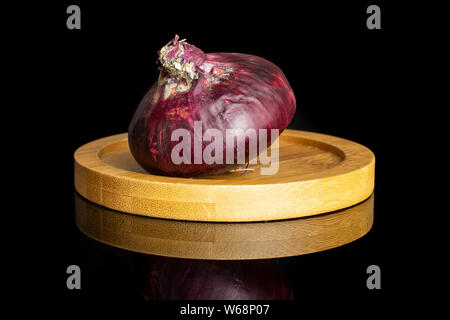 One whole stale red onion on bamboo plate isolated on black glass Stock Photo