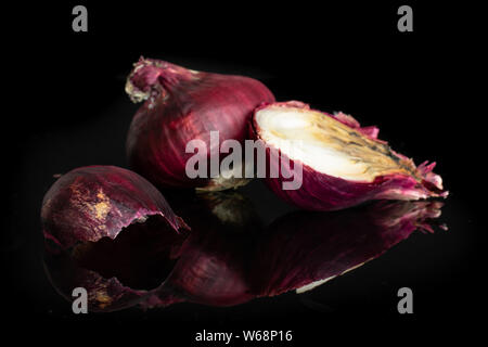 Group of one whole one half one piece of stale red onion isolated on black glass Stock Photo
