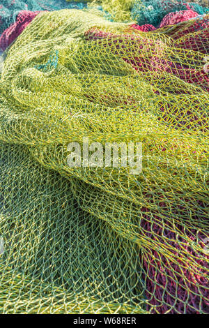Multi-colored fishing nets drying in the sun next to small fishing