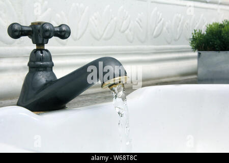 faucet coming out water in the white sink Stock Photo