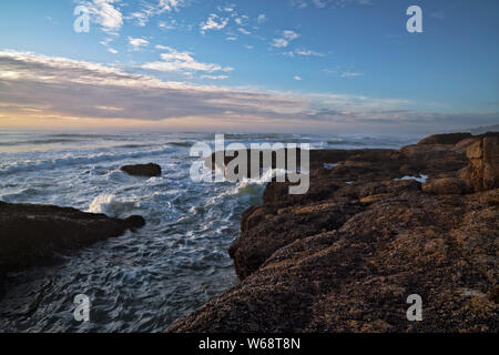 Evening light warmth on the surf and basalt shoreline along the central Oregon Coast at Yachats. Stock Photo